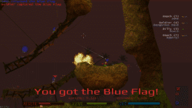 2D-gameplay fra Soldat, hvor en spiller bærer den blå flag på et skovlignende map. Eksplosioner lyser området op, mens flere spillere kæmper på træbroer og klippeformationer. HUD’en viser health, ammo og jet-fuel nederst, og scoreboardet ses til højre.