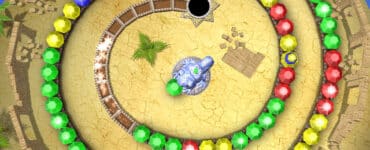 Skærmbillede fra Chameleon Gems, hvor spilleren skyder farvede perler mod en spiralførende kæde for at lave match-3 kombinationer på en sanddækket bane.