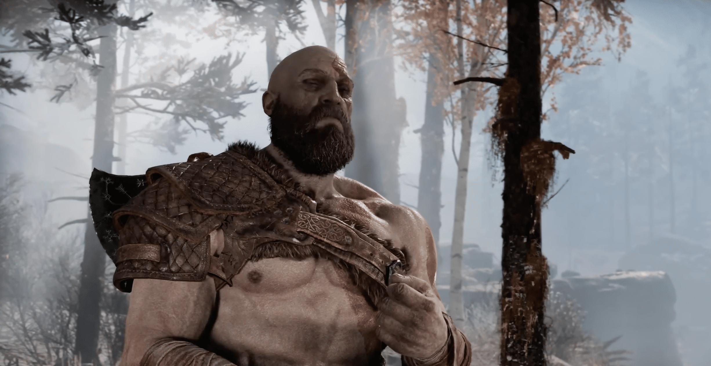 Lähikuva Kratoksesta sumuisessa metsässä; arpisella soturilla on haarniska ja vakava katse God of Warissa.