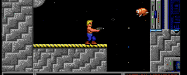 Screenshot fra vores test af Duke Nukem – Mission Moonbase, hvor Duke står på en månebaseplatform og skyder mod en flyvende robot i klassisk pixelgrafik fra DOS-æraen.