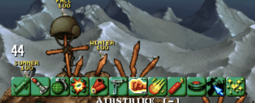 Gameplay fra Worms, hvor flere hold af orme kæmper i et ødelagt bjerglandskab med våbenmenu, vindindikator og sæsonbaseret HUD synlig på skærmen.