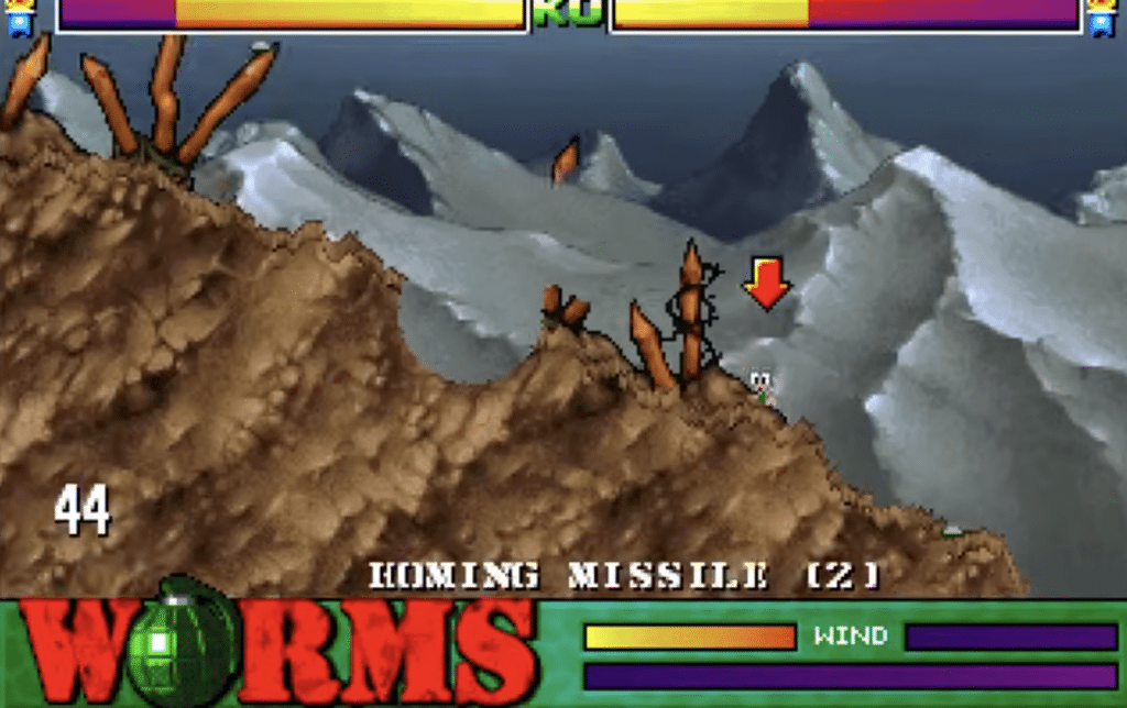 Gameplay fra Worms, hvor en enkelt orm er markeret som mål for et homing missile i et kuperet bjerglandskab med tydelig vindindikator og HUD-elementer.