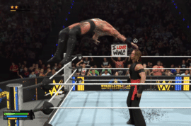 WWE 2K26 gameplay med wrestler, der springer fra hjørnet af ringen mod modstander foran et stort publikum.