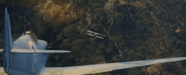 IL-2 Sturmovik viser en intens luftkamp, hvor et klassisk kampfly jager et fjendtligt fly tæt over et bjerglandskab.