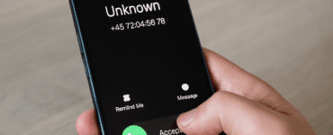 En hånd holder en smartphone, der viser et indgående opkald fra et ukendt nummer med teksten "Unknown" og et dansk telefonnummer, klar til at blive besvaret eller afvist.