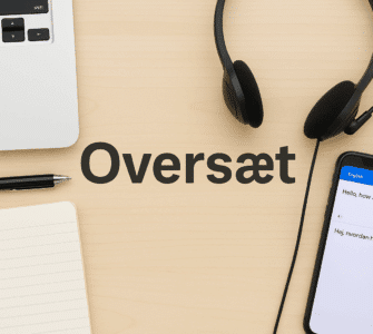 Et skrivebord med oversættelsesværktøjer – en bærbar computer, notesbog, kuglepen, headset og en smartphone med oversættelsesapp – med ordet "Oversæt" skrevet i midten på træoverfladen.