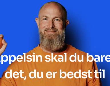 Mand med skæg holder en appelsin foran blå baggrund – Appelsin er en dansk regnskabsapp for selvstændige og små virksomheder