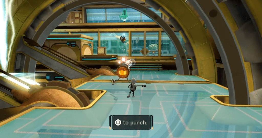 Screenshot aus Ratchet & Clank Future, in dem sich Clank durch eine futuristische Umgebung mit Glasböden, goldenen Konstruktionen und einem Tutorial-Hinweis zum Schlagen bewegt.
